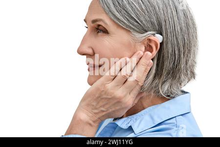 Middle-age woman with hearing impairment using hearing aid, side view. Hearing solutions for deafness people Stock Photo