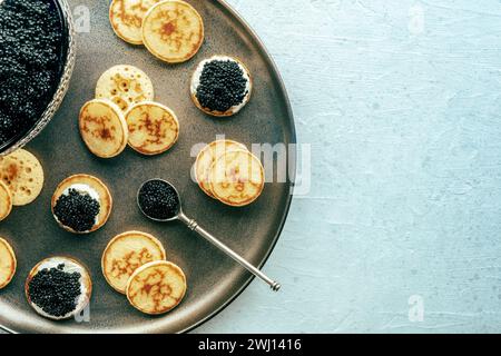 Blinis with black caviar and cream cheese, overhead flat lay shot Stock Photo