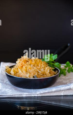 cabbage stewed with spices and carrots in a frying pan isolated on black background Stock Photo