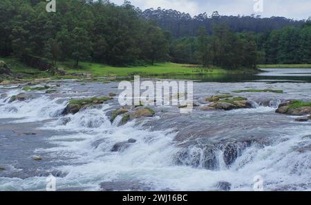 scenic landscape, lush green valley and beautiful pykara waterfall surrounded by pine forest and nilgiri mountains near ooty, tamilnadu, south india Stock Photo