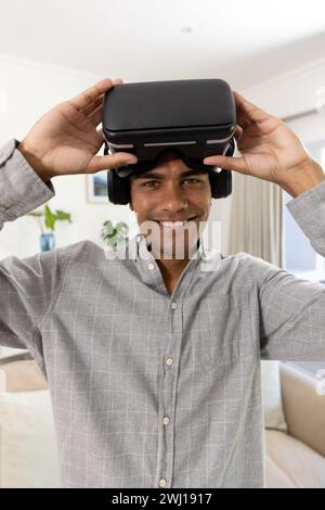 Portrait of happy biracial man using vr headset at home Stock Photo