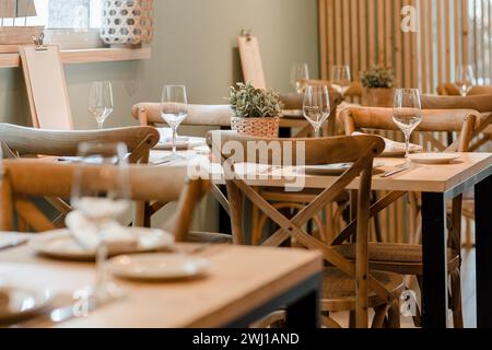 Elegant restaurant setting with wooden tables and wine glasses Stock Photo