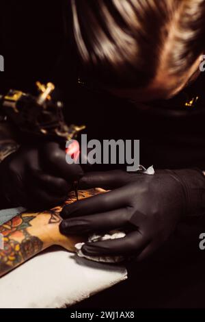 Close-up of tattoo artist working on intricate arm tattoo. Stock Photo