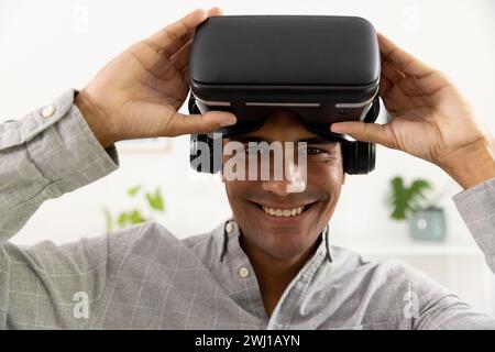 Portrait of happy biracial man using vr headset at home Stock Photo