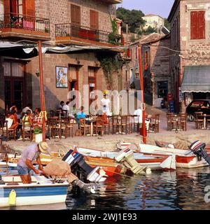Greece. Lesbos Island. Molyvos. Waterfront café & moored boats. Stock Photo
