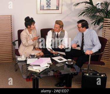 Business executives sitting around coffee table in office. Stock Photo