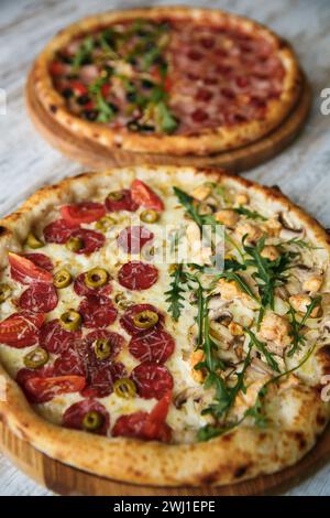 Two tasty different pizzas with variety of toppings and cheese on wooden table. top view Stock Photo