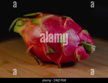 A dragonfruit on wooden table with dark backdrop Stock Photo