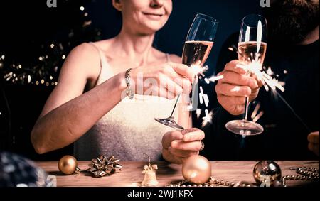 Happy couple holding sparkles and champagne glasses New Year party Stock Photo