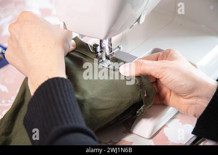 Detail of sewing work execution. Recycling clothes at home to reduce waste and avoid fast fashion. Woman sewing clothes at home. Stock Photo