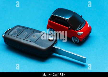 Extended car key and red toy car on blue background Stock Photo