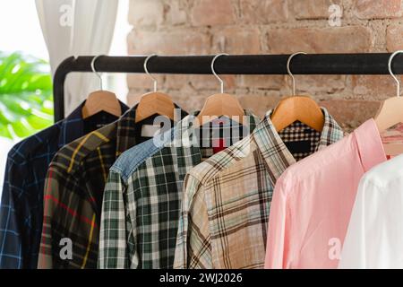 Clothing rack with variety of male shirts all hanging neatly on wooden hangers Stock Photo
