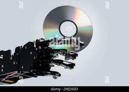 Real robotic hand with compact disc. Concepts of AI development and data storage Stock Photo