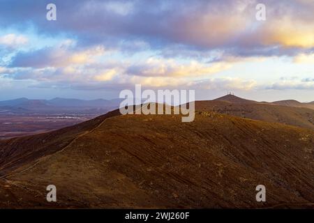 A serene landscape of rolling hills under a dramatic sky at dusk. Stock Photo