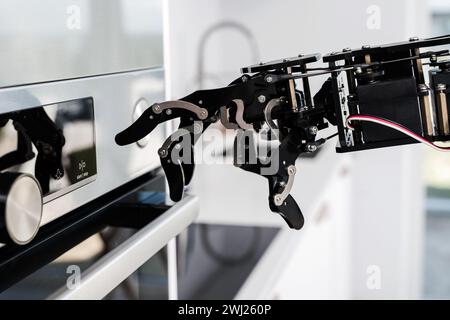 Real robot's hand and electric oven. Concept of robotic process automation Stock Photo