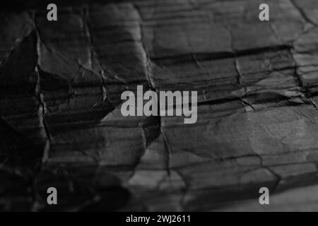 Crumpled black paper with wrinkles and folds. Dark cardboard abstract background Stock Photo