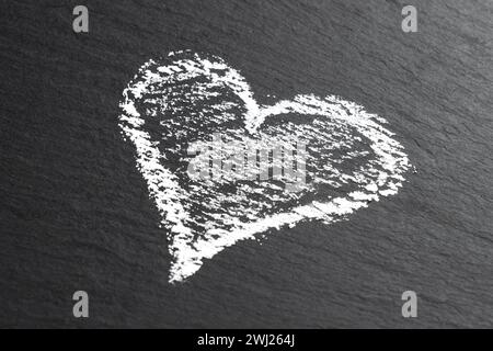 Heart drawn with white chalk on a black stone close up. Creative romantic art concept Stock Photo