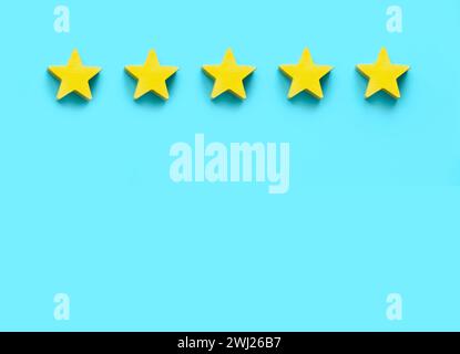 Client feedback, product rating, customer experience satisfaction. Five yellow wooden star on blue background with copy space. Stock Photo