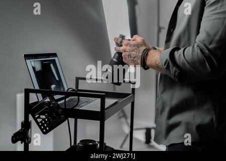 Closeup of the caucasian man photographer holding professional camera at dark photography studio Stock Photo