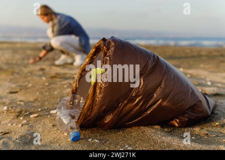 Woman volunteer is collecting plastic waste on the beach to contribute to the effort of keeping nature clean Stock Photo