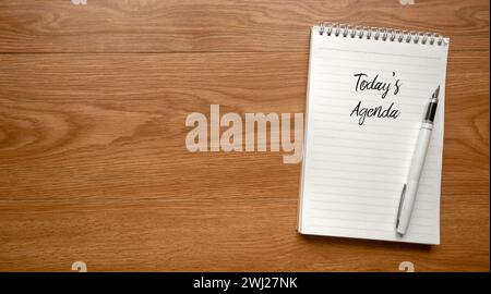 Top view of pen and notebook written with Today's Agenda on wooden background with copy space. Stock Photo