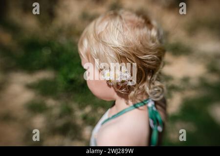 Side view of wildflowers tucked behind toddler girl's ear Stock Photo