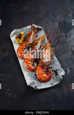 Traditional fried king prawns with pineapple pieces and black salt served as close-up on a design tray with text space Stock Photo