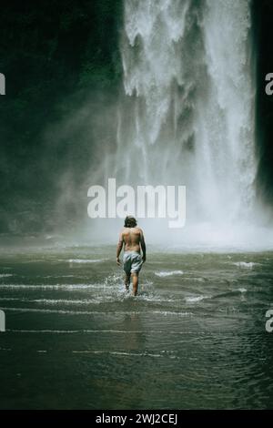 Man traveler, in the jungle, goes to the Nungnung waterfall. Bali Stock Photo