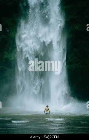 Man traveler, in the jungle, goes to the Nungnung waterfall. Bali Stock Photo