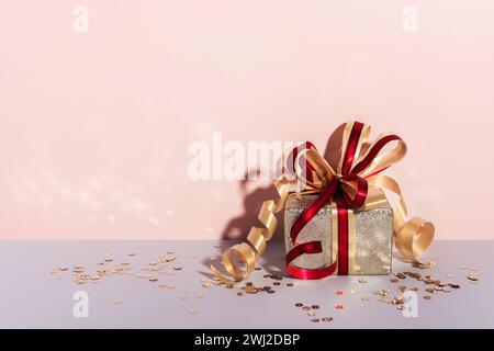 Festively wrapped gift box. Golden paper with ribbon and bow. Holiday Shopping concept Stock Photo