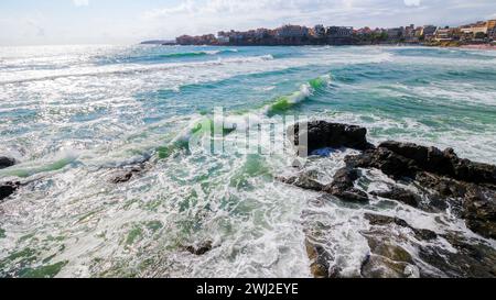 sozopol, bulgaria - 09 aug 2015: cityscape of the old town at the sea. waves crashing on the rocky coast in morning light. beautiful travel destinatio Stock Photo