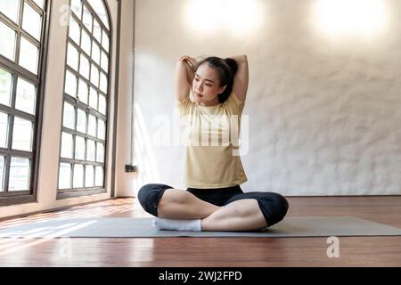 Female girl Attractive young asian woman doing stretching exercise on mat yoga Calmness and relax at gym Full body concentratedÂ Stock Photo