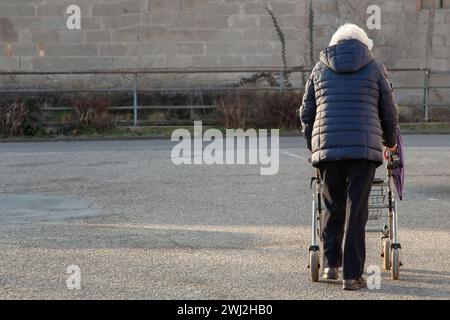 Old lady, senior woman with rollator for a walk on the street. Grandma with wheeled walker. Stock Photo