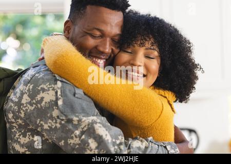 Happy african american male soldier embracing wife at home Stock Photo