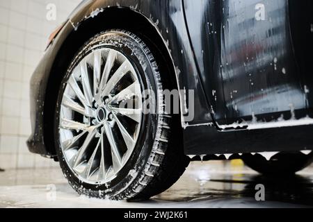 object photo of shining tired of black modern auto covered with soap during car detailing service Stock Photo