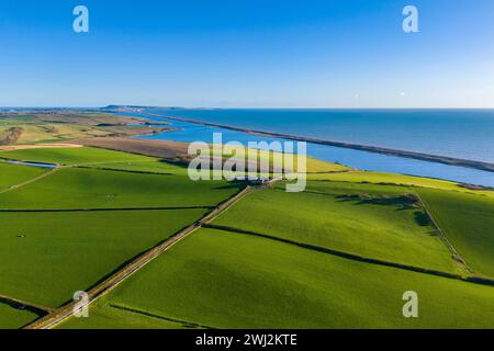 Abbotsbury, Dorset, UK.  12th February 2024.  UK Weather.  Aerial view across fields at Abbotsbury in Dorset looking along Chesil Beach and the Fleet lagoon to the Isle of Portland on the Jurassic Coast on a warm sunny afternoon.  Picture Credit: Graham Hunt/Alamy Live News Stock Photo