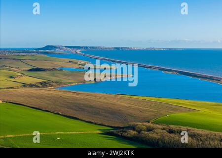 Abbotsbury, Dorset, UK.  12th February 2024.  UK Weather.  Aerial view across fields at Abbotsbury in Dorset looking along Chesil Beach and the Fleet lagoon to the Isle of Portland on the Jurassic Coast on a warm sunny afternoon.  Picture Credit: Graham Hunt/Alamy Live News Stock Photo