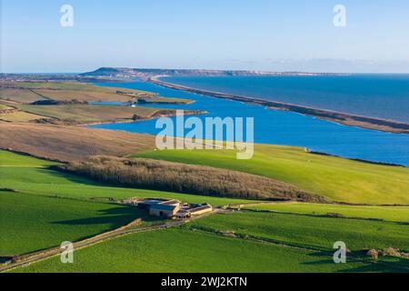 Abbotsbury, Dorset, UK.  12th February 2024.  UK Weather.  Aerial view across fields at Abbotsbury in Dorset looking along Chesil Beach and the Fleet lagoon to the Isle of Portland on the Jurassic Coast on a warm sunny afternoon.  Picture Credit: Graham Hunt/Alamy Live News Stock Photo