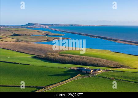 Abbotsbury, Dorset, UK.  12th February 2024.  UK Weather.  Aerial view across fields at Abbotsbury in Dorset looking along Chesil Beach and the Fleet lagoon to the Isle of Portland on the Jurassic Coast on a warm sunny afternoon.  Picture Credit: Graham Hunt/Alamy Live News Stock Photo