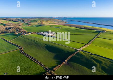 Abbotsbury, Dorset, UK.  12th February 2024.  UK Weather.  Aerial view across fields at Abbotsbury in Dorset looking along Chesil Beach and the Fleet lagoon to the Isle of Portland on the Jurassic Coast on a warm sunny afternoon.  Picture Credit: Graham Hunt/Alamy Live News Stock Photo