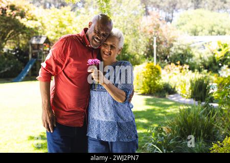 Happy diverse senior couple embracing in sunny garden Stock Photo