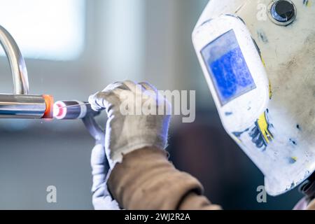 a man wearing a welding mask is welding a pipe Stock Photo