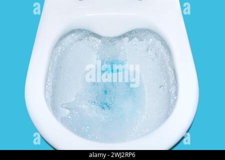 Toilet bowl flush with blue cleaning fluid isolated. cleaning Toilet close-up. Environmental polluti Stock Photo