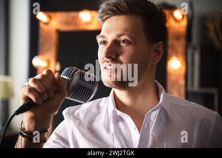 Young man with microphone is singing at home Stock Photo