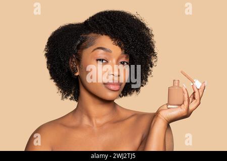 Serene young black woman presenting liquid foundation bottle Stock Photo