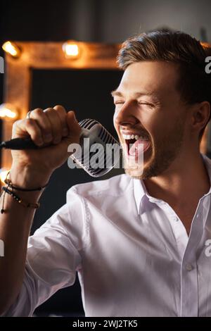 Young man with microphone is singing at home Stock Photo