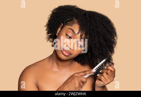 Black woman gently detangling her curly hair Stock Photo
