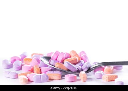 Closeup shot of spoon and pile of pills on white background. Stock Photo