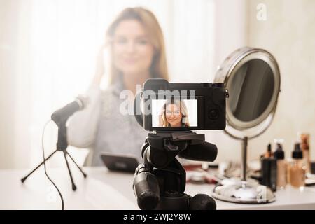 Modern mirrorless camera recording video of beauty blogger's make-up routine Stock Photo