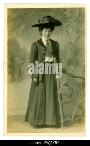 Original Edwardian era postcard of attractive lady, called Nellie. who appears to be a feminist, (from the back of the postcard) wearing a large hat., very typical of this era. Edwardian lady. Edwardian ladies. She wears a long skirt with a long jacket over it. circa1909, U.K. Stock Photo